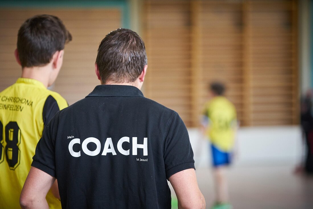 Badmintontrainer die tips geeft aan spelers in de sporthal