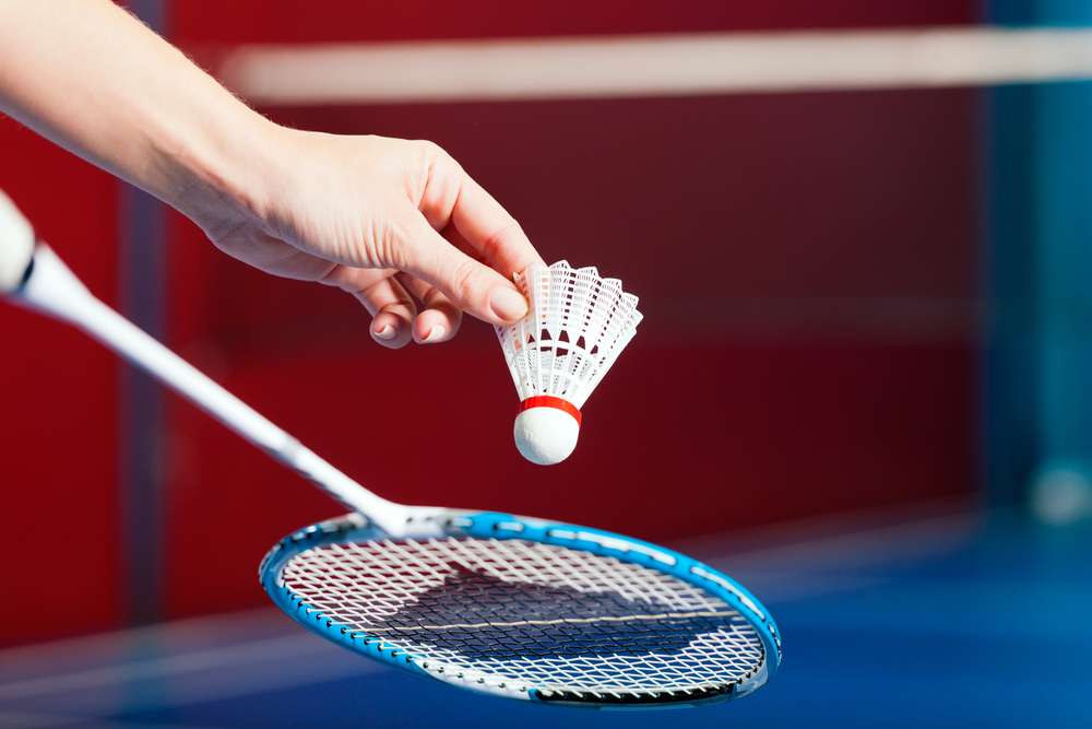 Badmintonspelers die lachen en elkaar high five geven in de sporthal